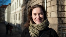 Young woman smiling on a Berlin street during winter, enjoying the bright day.