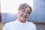 Portrait of a smiling senior woman with eyeglasses enjoying a sunny day outdoors.